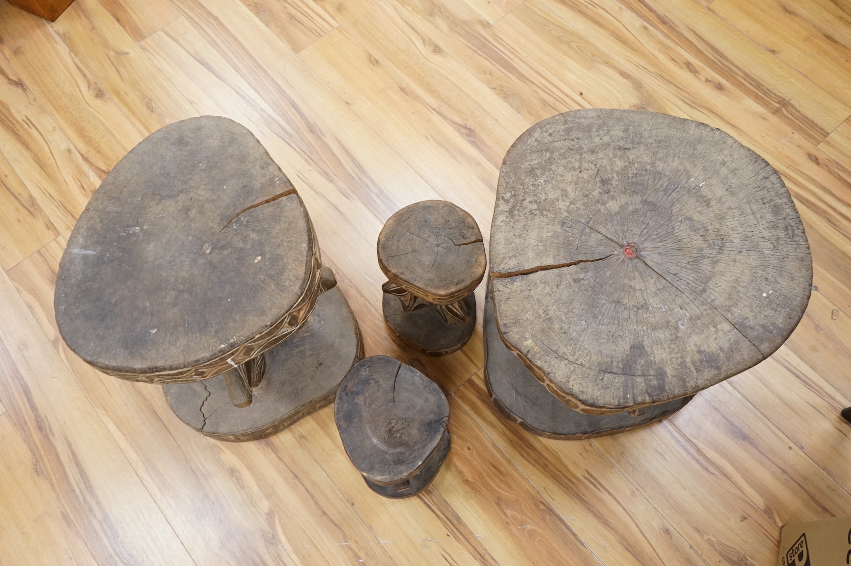 Papua New Guinea Sepik River, two tribal tables, each carved from a section of tree trunk, with circular top and base, the supports and edges incised and painted with geometric designs and two other small stools, largest